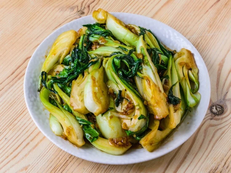 pak choi sauté dans une assiette blanche sur fond de bois