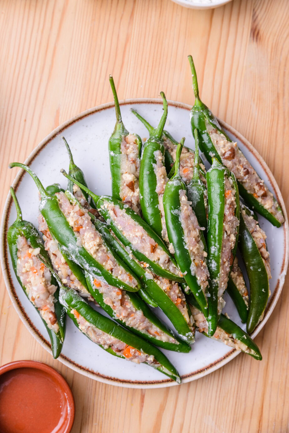 Piments verts farcis à la viande et légumes, présentés sur une assiette blanche.