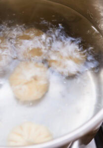 Des raviolis cuisent dans une casserole d’eau bouillante.