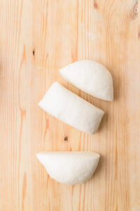 Trois morceaux de pâte à pain sur une planche en bois.