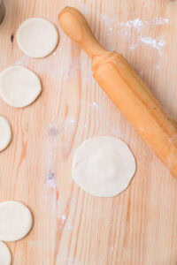 Disques de pâte et rouleau à pâtisserie sur une table en bois farinée.