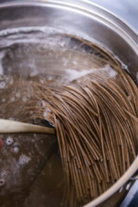 Des nouilles soba en train de cuire dans une casserole d'eau bouillante.
