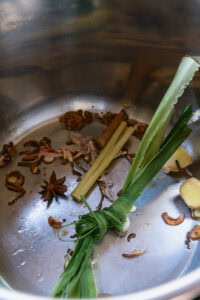 Épices et herbes (citronnelle, badiane, gingembre, cannelle) dans une casserole en inox.