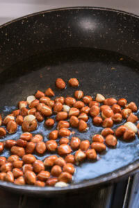 Cacahuètes en train de frire dans une poêle avec de l'huile.