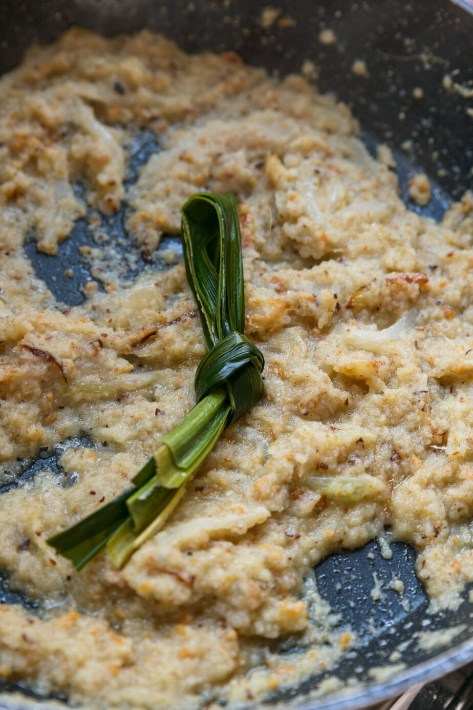 フライパンの中央に結んだパンダンリーフが入ったクリーミーな混合物。