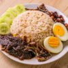 Assiette de nasi lemak avec riz, œuf dur, concombre, anchois, cacahuètes et sambal.