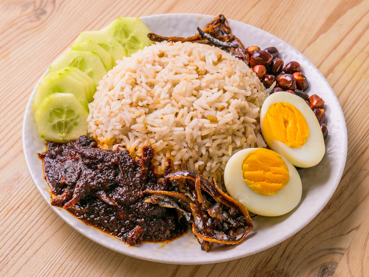 Assiette de nasi lemak avec riz, œuf dur, concombre, anchois, cacahuètes et sambal.