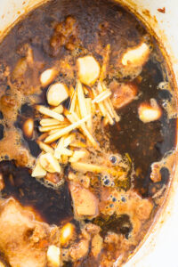 Gaeng Hang Lay - Ajouter l’ail vinaigré, le masala Hang Lay, le gingembre et les gousses d’ail entières.