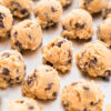 Boules de pâte à cookies aux pépites de chocolat disposées sur une plaque de cuisson.