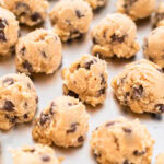 Boules de pâte à cookies aux pépites de chocolat disposées sur une plaque de cuisson.
