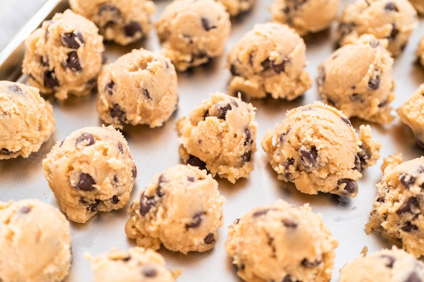 Boules de pâte à cookies aux pépites de chocolat disposées sur une plaque de cuisson.