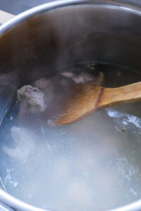 Morceaux de viande bouillant dans une casserole d’eau, remués avec une cuillère en bois.