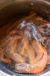 Des crevettes entières sont en train de cuire dans une casserole d’eau bouillante.