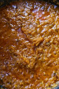 Sauce tomate épaisse et mijotée, de couleur rouge orangé, avec une texture granuleuse.