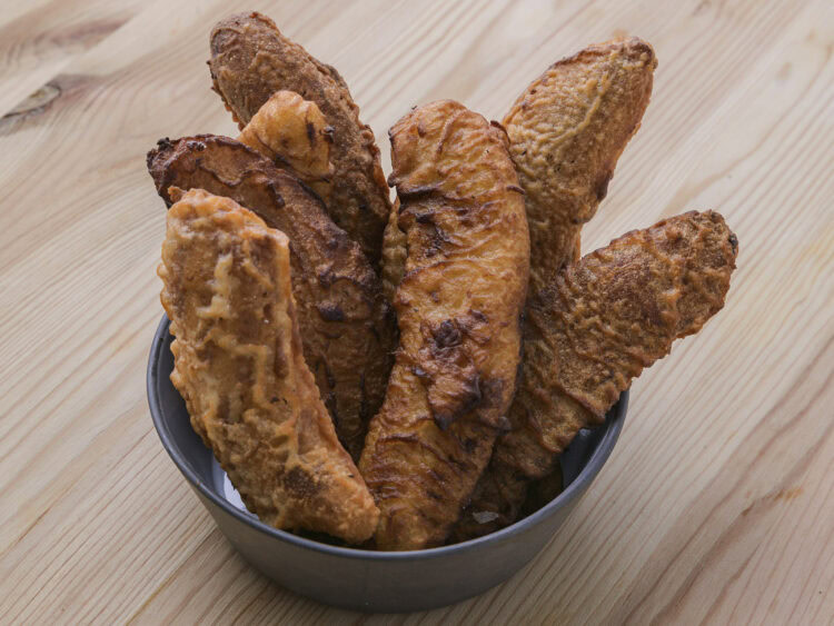 Bananes frites croustillantes dans un bol sur une table en bois.