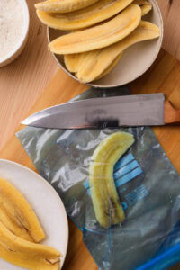 Beignets de banane (Bánh Chuối Chiên) - Glisser chaque demi-banane dans un sac plastique propre et l'aplatir délicatement avec le plat d'un couteau ou une planche.