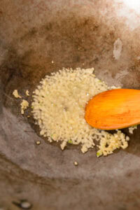 Khao Kluk Kapi - Chauffer l’huile dans un wok et faire frire l’ail jusqu’à bien parfumé.