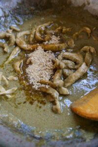 Morceaux de viande cuits dans une sauce épaisse avec des épices en poudre, mélangés dans une poêle.