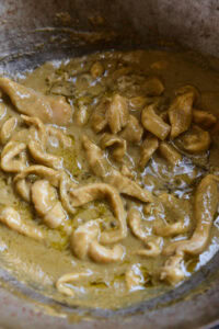 Morceaux de viande cuits dans une sauce crémeuse jaune, dans une casserole.