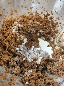 Mélange de sucre brun et de crème dans un bol en métal, prêt pour une recette de pâtisserie.