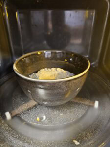 Bol avec de la poudre à l'intérieur, placé sur le plateau tournant d'un micro-ondes.