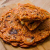 Galette coréenne au kimchi coupée en parts, servie sur une planche en bois.