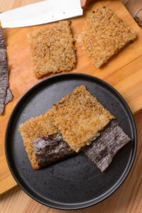 Riz coréen grillé (Nurungji) - Lorsque le croustillant souhaité est atteint, transférer le riz sur une planche, le couper en 4 morceaux, couper la feuille de nori en rectangles et plier chaque rectangle à la base de chaque morceau