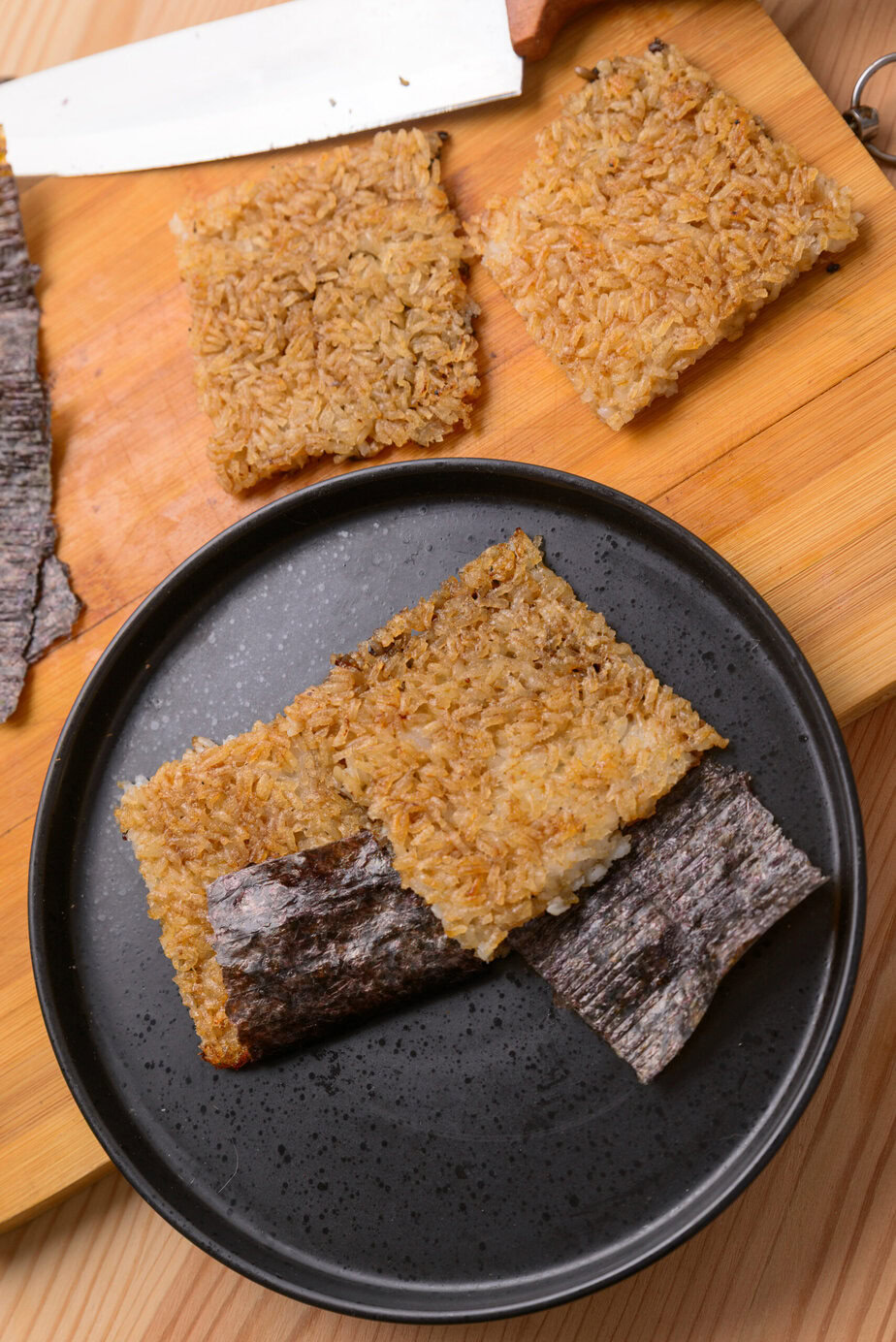 Riz coréen grillé (Nurungji) - Lorsque le croustillant souhaité est atteint, transférer le riz sur une planche, le couper en 4 morceaux, couper la feuille de nori en rectangles et plier chaque rectangle à la base de chaque morceau