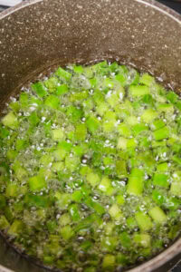 Des morceaux de ciboulette cuisent dans de l'eau bouillante dans une casserole.