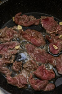 Tapsilog - Déposer le bœuf en une seule couche sans surcharger la poêle, puis cuire en le retournant, environ 3 à 5 minutes, jusqu’à ce qu’il rende son jus et que le liquide soit presque absorbé.