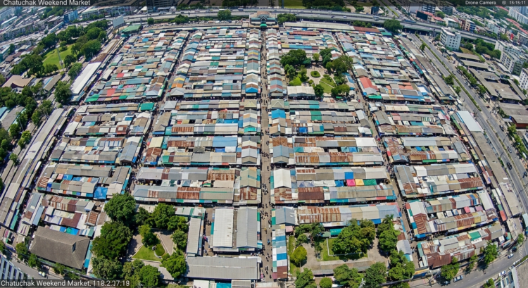 Vue aérienne du marché Chatuchak à Bangkok, avec ses nombreuses allées couvertes et des arbres autour.