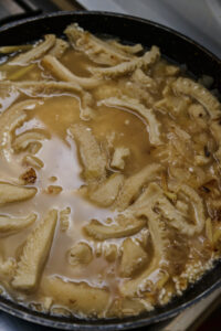 Tripes en cuisson dans une casserole avec bouillon et oignons.