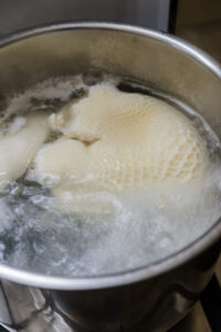 Tripes de bœuf en train de bouillir dans une casserole d'eau sur une cuisinière.