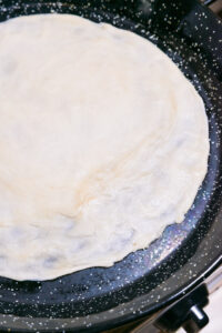 Martabak telur - Finition: Étirer en appuyant avec les pouces et les doigts jusqu’à obtenir une pâte très fine et presque transparente.