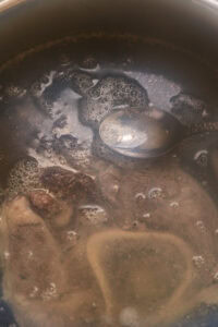 Recette de bulalo - Écumer les impuretés qui flottent sur le bouillon.