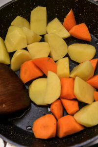 bifu kare - Faire revenir la carotte et la pomme de terre, puis les cuire dans du bouillon jusqu’à cuisson, en ajustant le feu pour éviter que la pomme de terre ne se défasse.
