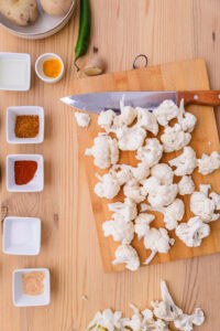 Aloo Gobi (Chou-fleur aux pommes de terre) - Retirer les tiges du chou-fleur, couper en petits morceaux et mettre les fleurettes dans de l'eau tiède salée pendant 5 minutes