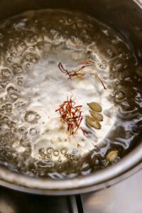 Gulab Jamun - Ajouter les capsules de cardamome et laisser cuire jusqu'à ce que le sirop commence à prendre un peu de consistance.