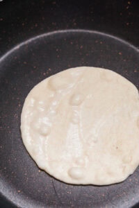 Naan - Quand des bulles apparaissent sur le pain, retourner la poêle au-dessus de la flamme de la cuisinière en gardant le pain collé