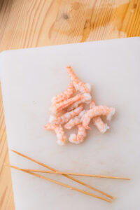 Authentique Chirashi - Laisser refroidir, retirer les brochettes, décortiquer, couper les crevettes en deux dans la longueur, puis les faire mariner dans le vinaigre, le sucre et le dashi.
