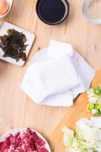 Authentique Sukiyaki - Éponger soigneusement le tofu grillé avec du papier absorbant, puis le couper en 8 morceaux.