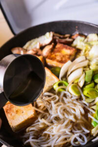 Authentique Sukiyaki - Enrober le tofu avec le gras du bœuf. Attendre que les légumes s'attendrissent. Ajouter un peu de bouillon de kombu si le fond risque d'attacher.