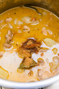 Curry massaman - Ajouter le sucre de palme, la sauce poisson, le jus de tamarin et le jus d’orange.