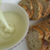 Tranches de pain à côté d’un bol de sauce crémeuse blanche.