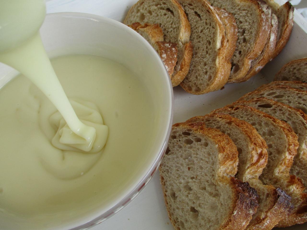 Tranches de pain à côté d’un bol de sauce crémeuse blanche.