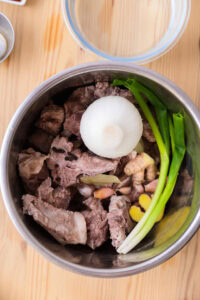 Authentique Gamjatang - Mettre les os d’échine de porc blanchis dans une marmite avec les ingrédients de l’eau de cuisson de la viande.
