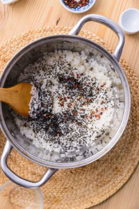 Authentique Inari Sushi - Mélanger le riz délicatement en coupant avec une spatule. Ajouter graines de sésame et baies de sanshō.