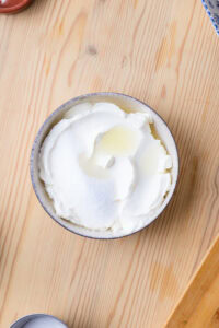 Bol de crème fouettée blanche sur une table en bois clair.