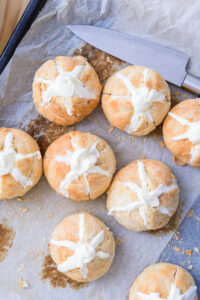 Petits pains dorés fourrés de crème, posés sur une plaque de cuisson avec un couteau.