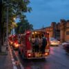 Taxis rouges bondés près d’un vieux mur en briques, au bord d’un canal, au crépuscule.